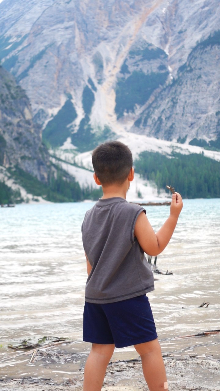 A child standing by a mountain lake before turning toward the camera