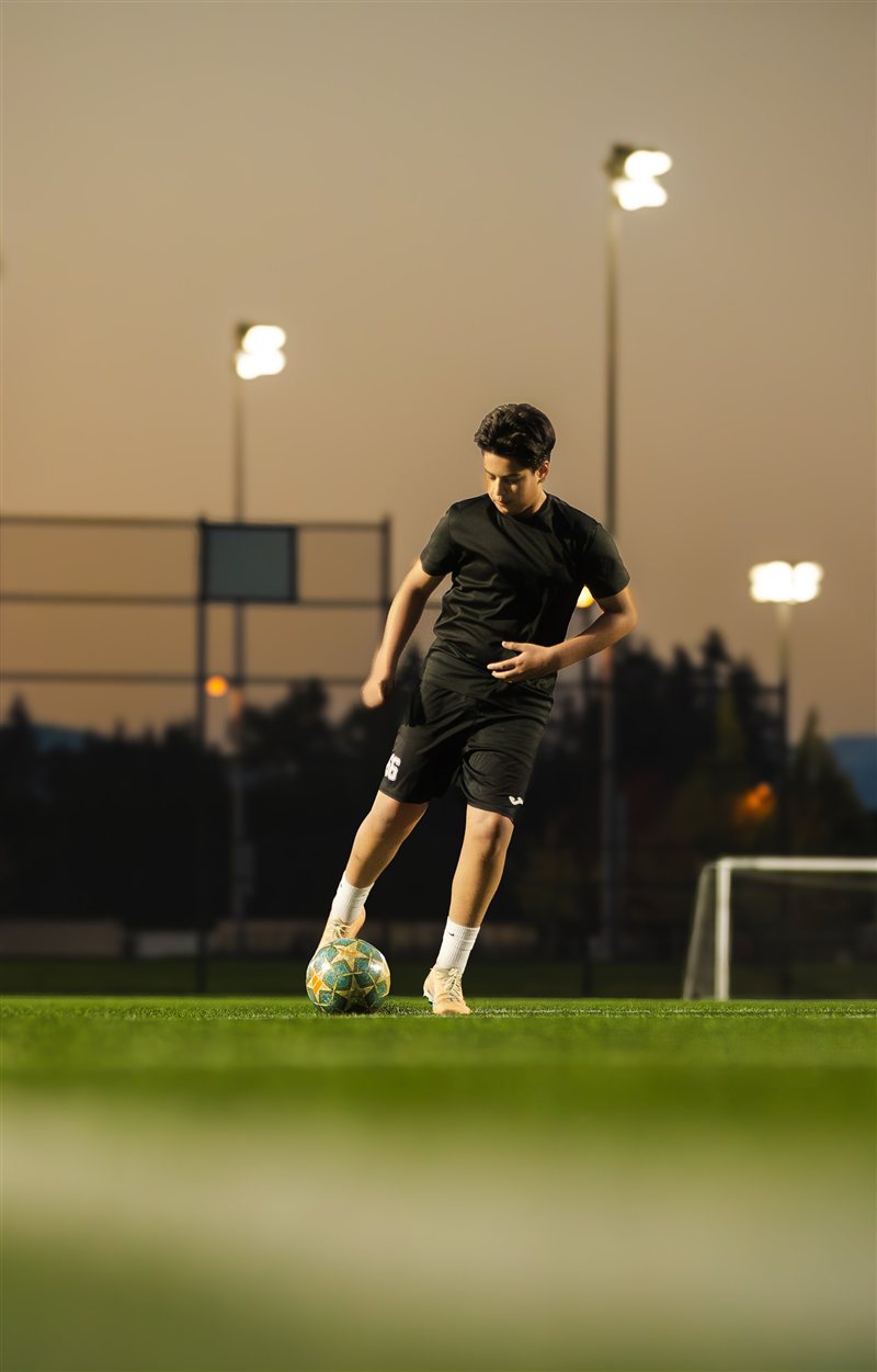 Soccer player striking the ball at dusk